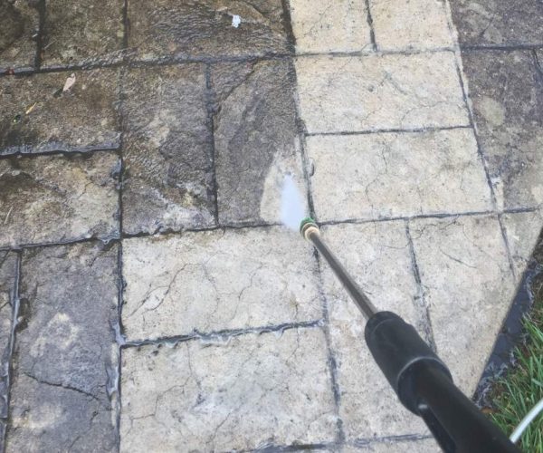 pressure washer spraying concrete before and after cleaning