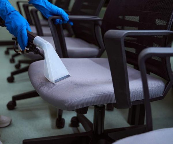 professional in blue gloves cleaning upholstery on office chairs