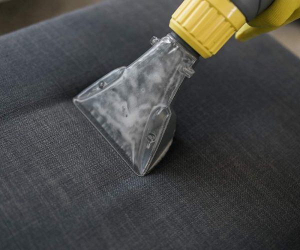 professional in yellow glove cleaning gray commercial upholstery